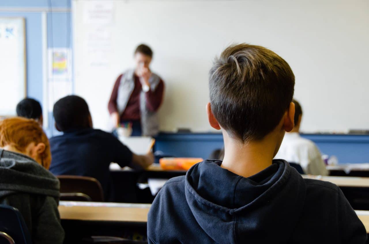 Behind view of children sitting in a classroom setting.