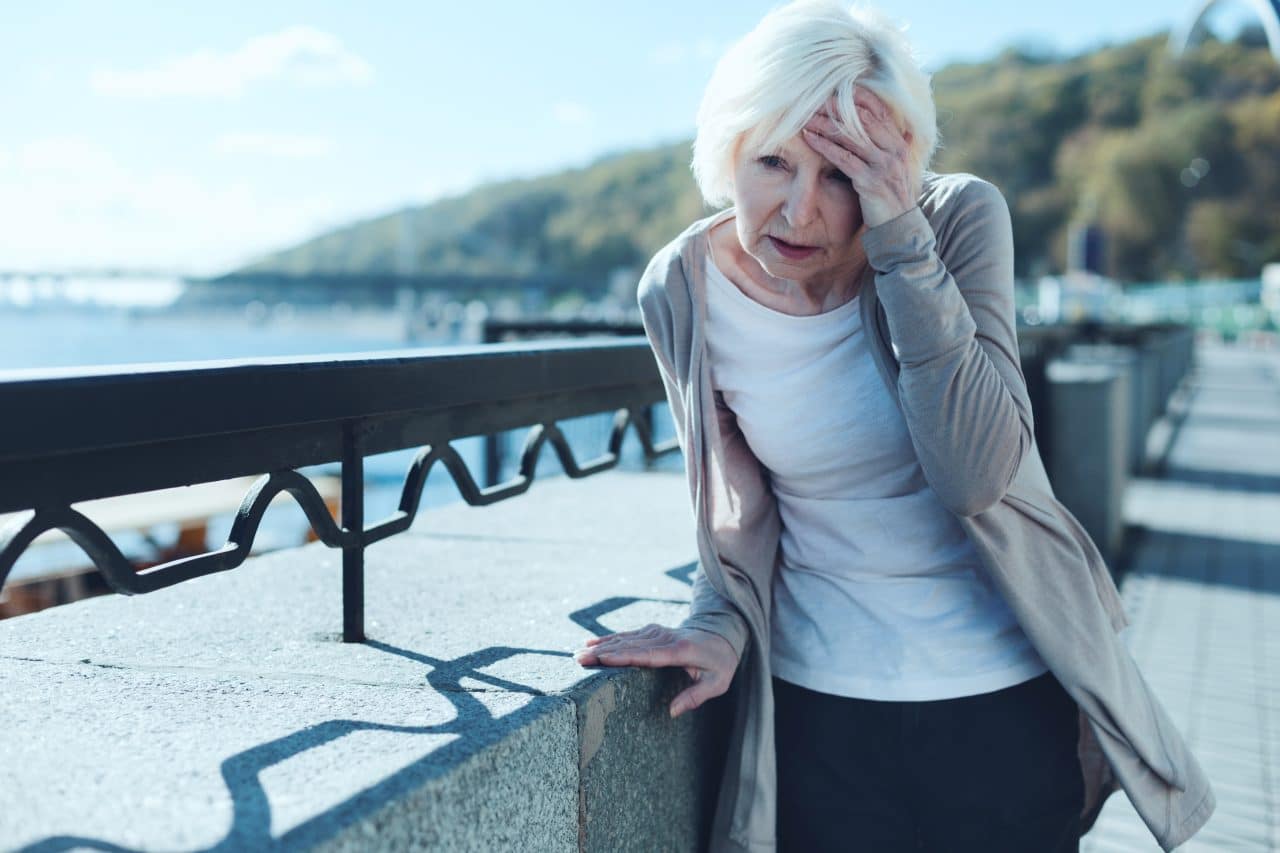 Senior woman feeling dizzy and off balance while out for a walk.