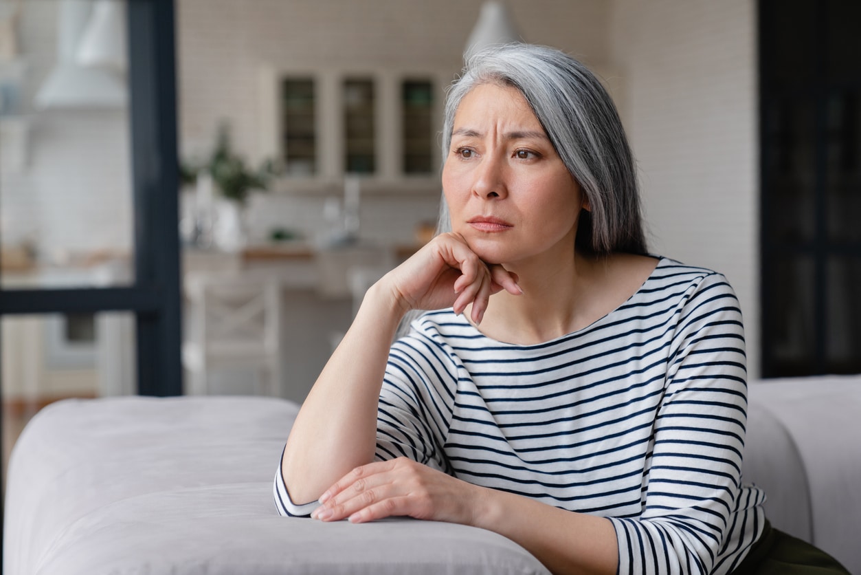 Woman with a sad expression sitting alone at home.