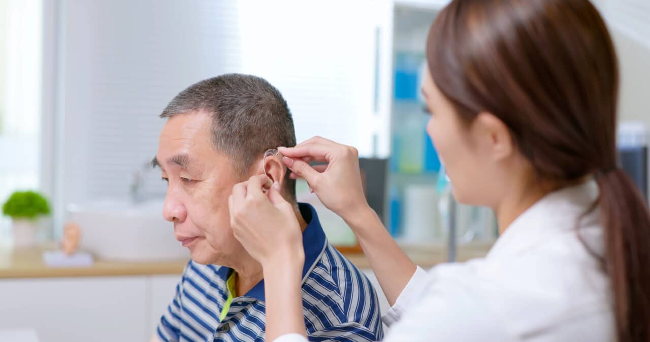 Man being fit for a hearing aid to help with his tinnitus.