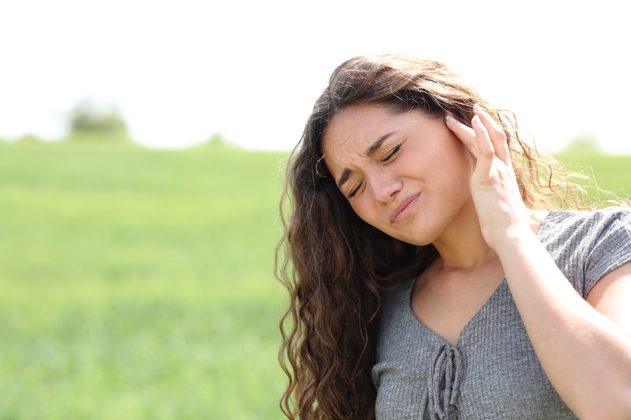 Woman with tinnitus holding her ear.
