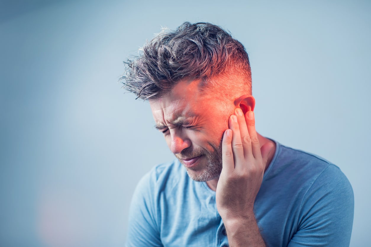 Man with tinnitus holds ear