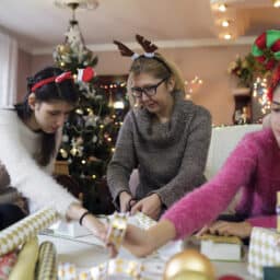 Young girl wearing a hearing aid wrapping gifts with her family