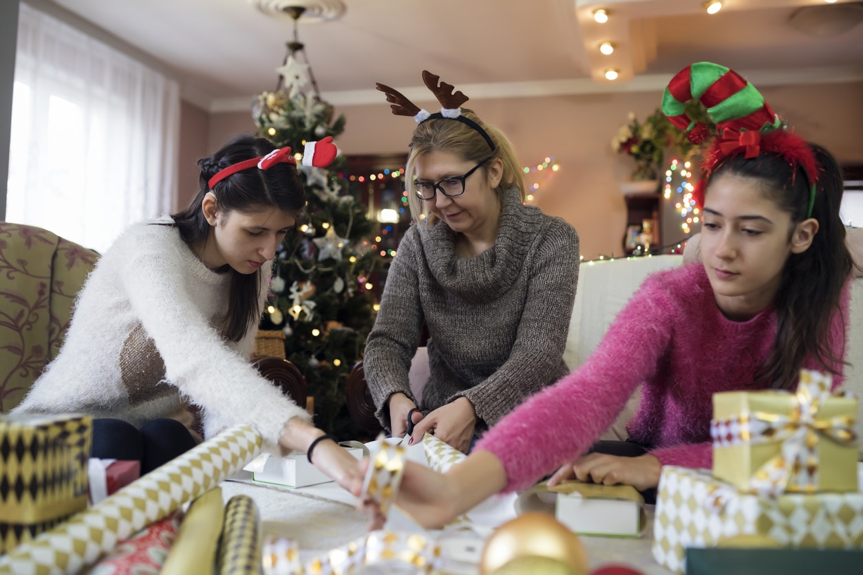 Young girl wearing a hearing aid wrapping gifts with her family.