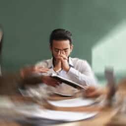 Man with stress tinnitus in a meeting holding his face