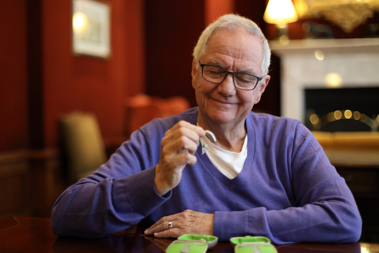 Senior man looking at his hearing aid.