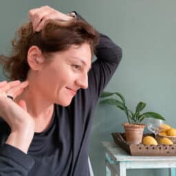 A woman adjusts her hearing aid confidently.